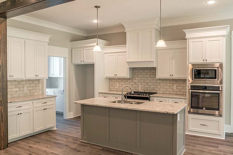 Gourmet kitchen in Farmhouse Plan 56911 featuring a large island, butler’s pantry, shaker cabinets, and open-concept layout with 10-foot ceilings